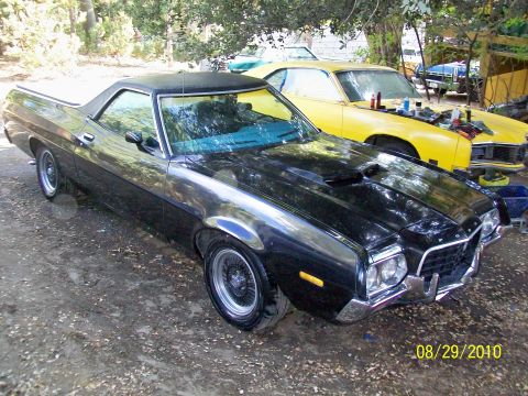 1972 Ford Ranchero - A black 1972 Ford Ranchero is parked next to a yellow car with its hood open.
