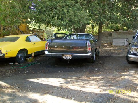 1972 Ford Ranchero - Rear view of a dark 1972 Ford Ranchero pickup truck parked next to a yellow car.