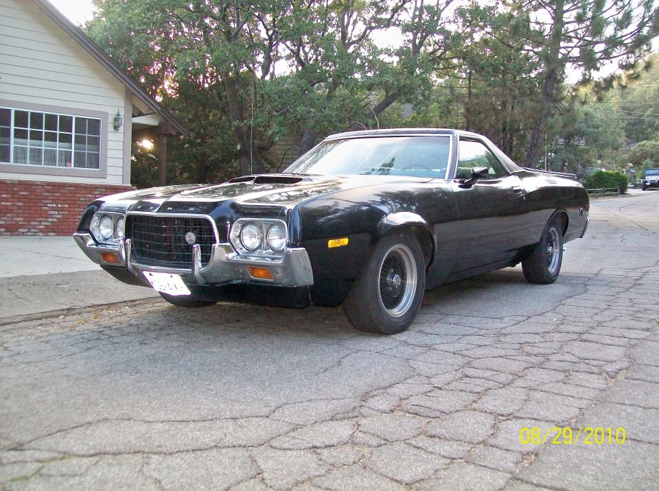 Black Ford Ranchero car-pickup parked in driveway, front 3/4 view