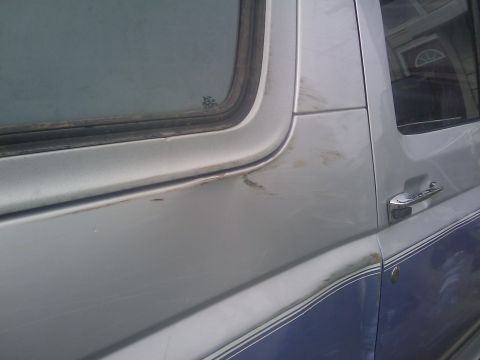 1996 Ford Bronco - Side view of a 1996 Ford Bronco showing its two-tone silver and blue paint scheme and chrome door handle.