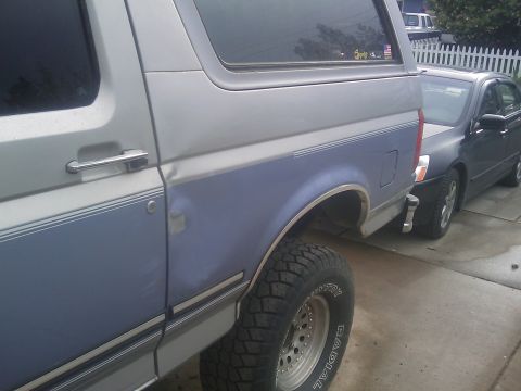 1996 Ford Bronco - The side of a two-tone Ford Bronco is shown parked next to another vehicle.