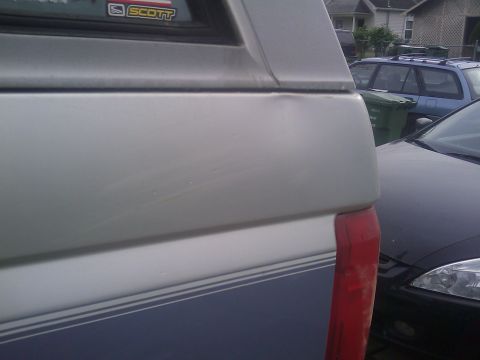 1996 Ford Bronco - Rear quarter panel view of a silver and blue 1996 Ford Bronco, showing its taillight and side trim.