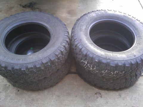 1996 Ford Bronco - Two off-road tires are shown stacked on a concrete surface. One tire has 'WILDCAT' visible on its sidewall.
