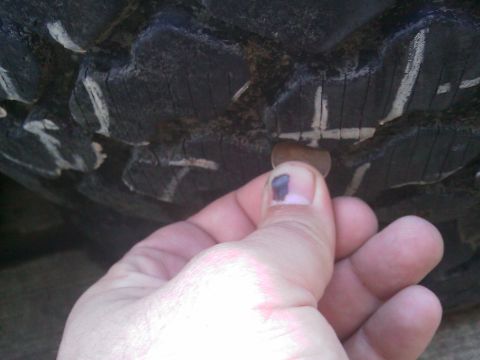 1996 Ford Bronco - A penny is used to check the tread depth on a tire, which has white markings on its surface.