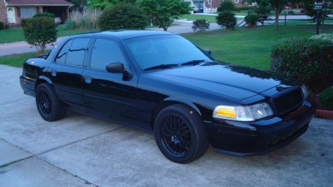 2004 Ford Crown Victoria - This black sedan is parked in a suburban driveway, showing its front three-quarter view.