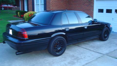 2004 Ford Crown Victoria - A black 2004 Ford Crown Victoria is parked in front of a brick house and garage.