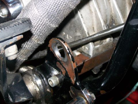 1988 Suzuki Samurai - Close-up view of a motorcycle's engine component, showing a heat-shielded hose and a bracket with visible rust.