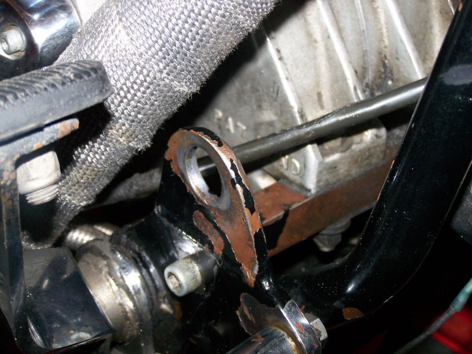 Motorcycle engine part with heat-shielded hose and rusty bracket