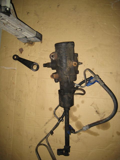 1988 Ford Bronco - A disassembled power steering gearbox and linkage assembly is shown on a flat surface.