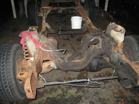 1988 Ford Bronco - This is a photo of a heavily rusted vehicle frame, showing suspension parts and tires.