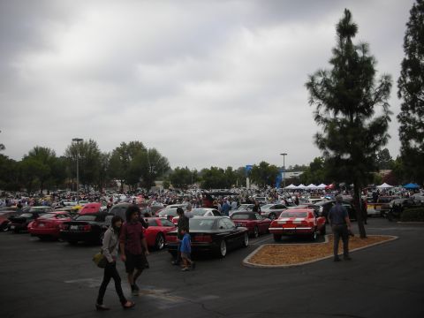 1998 Ford Crown Victoria - A large gathering of cars and people at an outdoor event under a cloudy sky.