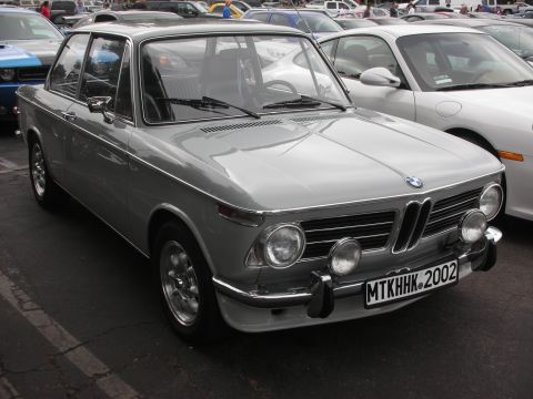 1998 Ford Crown Victoria - A silver BMW 2002 is parked at a car meet, with other vehicles visible in the background.