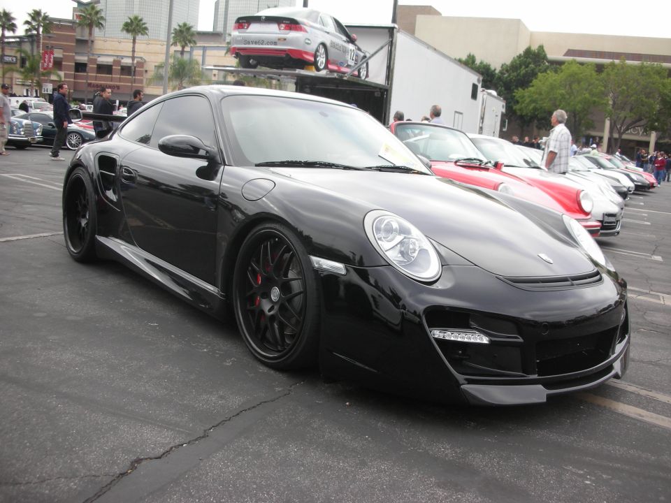 Black Porsche 911 Turbo parked in lot, other cars in background