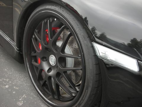 1998 Ford Crown Victoria - Close-up of a black car's wheel and tire, revealing red brake calipers.