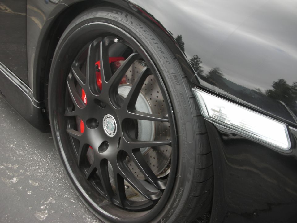 Black car wheel with red brake calipers and custom rims