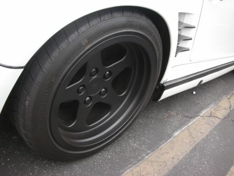 1998 Ford Crown Victoria - Close-up of a white car's wheel black five-spoke rims and a Yokohama tire.