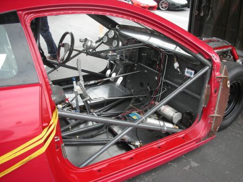 1998 Ford Crown Victoria - Interior view of a modified red race car with a roll cage and racing seat.
