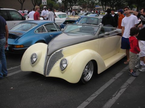 1998 Ford Crown Victoria - A custom 1939 Ford convertible is parked at a car meet, with other vehicles and people around.