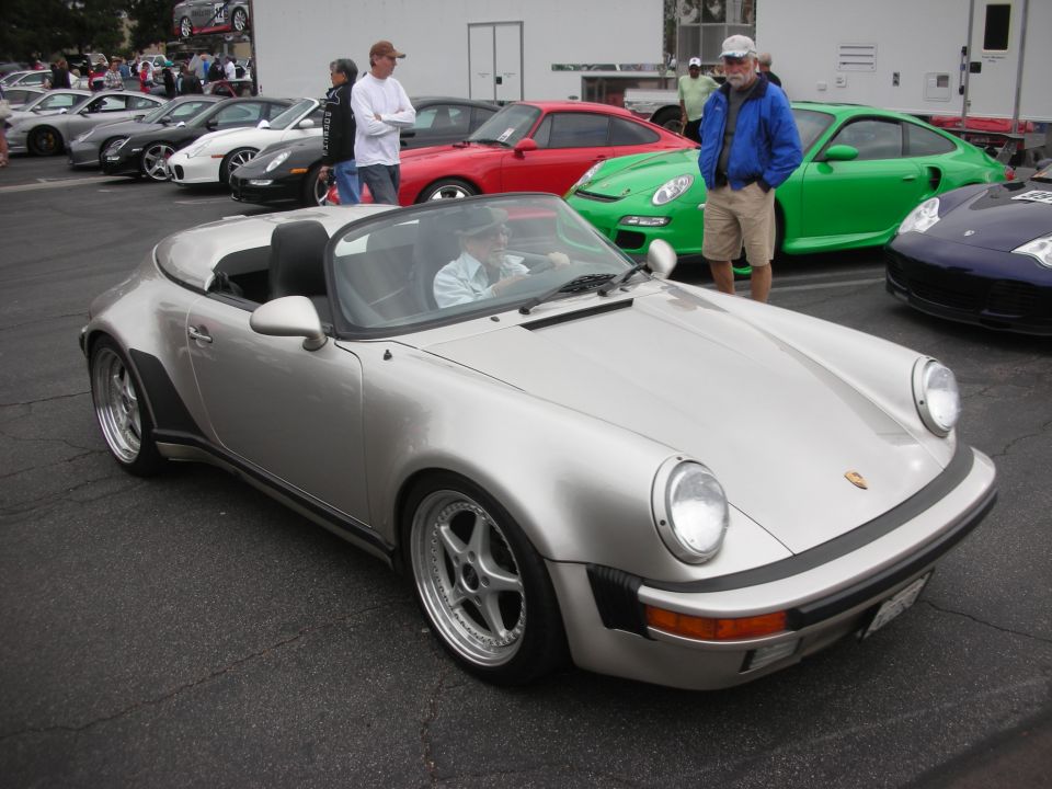 Silver convertible sports car with black trim and aftermarket wheels, parked on asphalt