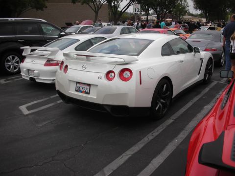 1998 Ford Crown Victoria - A white Nissan GT-R is parked in a lot with other vehicles, showing its distinctive taillights and spoiler.