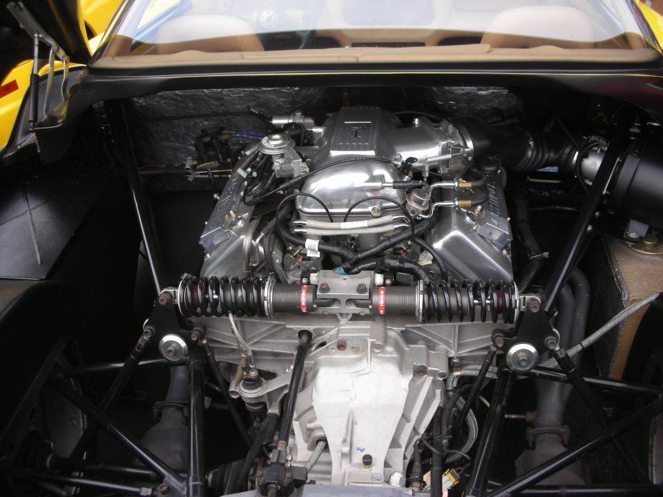 Engine bay with V8 engine, chrome intake manifold, and suspension components visible