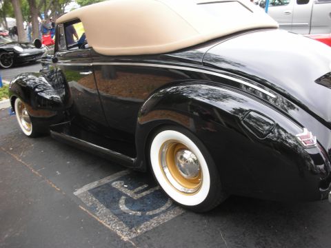 1998 Ford Crown Victoria - A classic black convertible with a tan top is parked in a handicapped spot, with another car in the background.