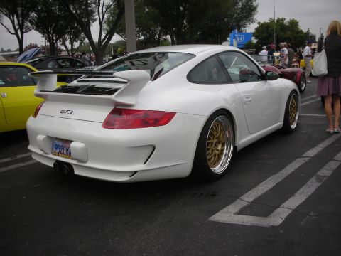 1998 Ford Crown Victoria - A white Porsche GT3 is parked in a lot, gold rims and a prominent rear spoiler.