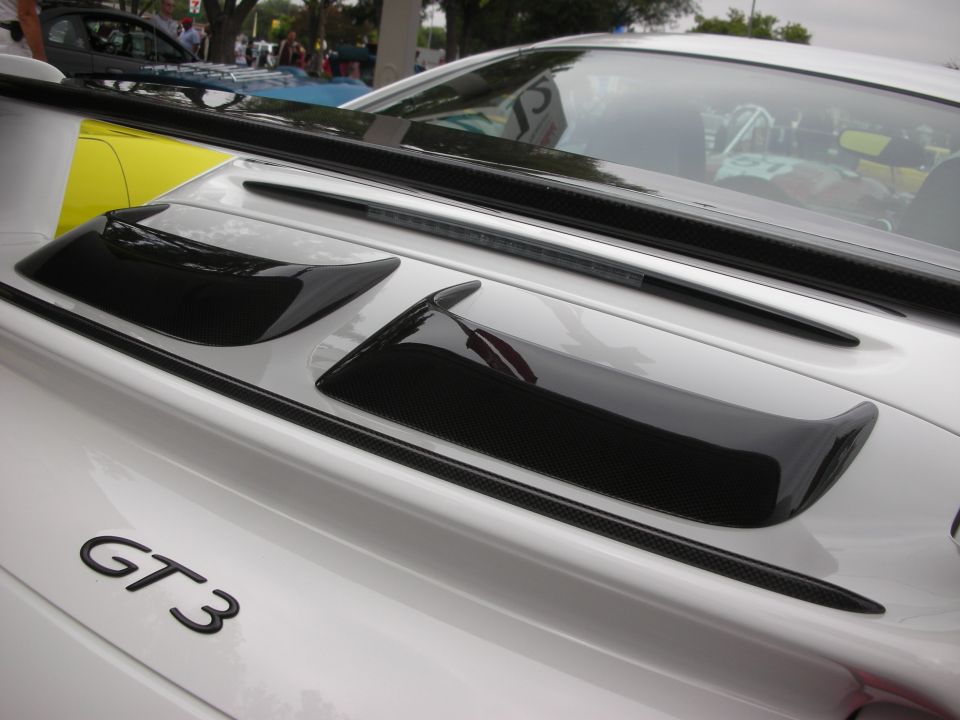 Close-up of a white Porsche GT3's rear decklid with carbon fiber accents and a spoiler