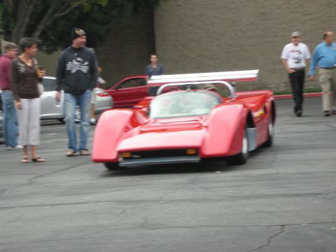1998 Ford Crown Victoria - A red race car is the focus of this photo, with several people standing nearby.