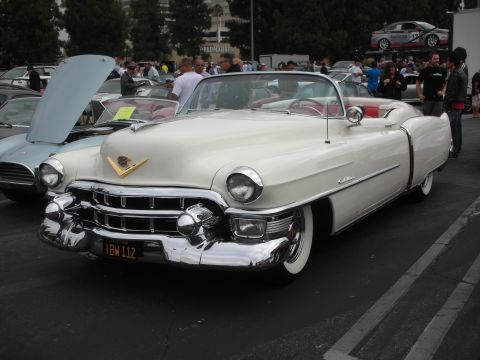 1998 Ford Crown Victoria - A classic white convertible is parked at a car meet, with other vehicles and people in the background.