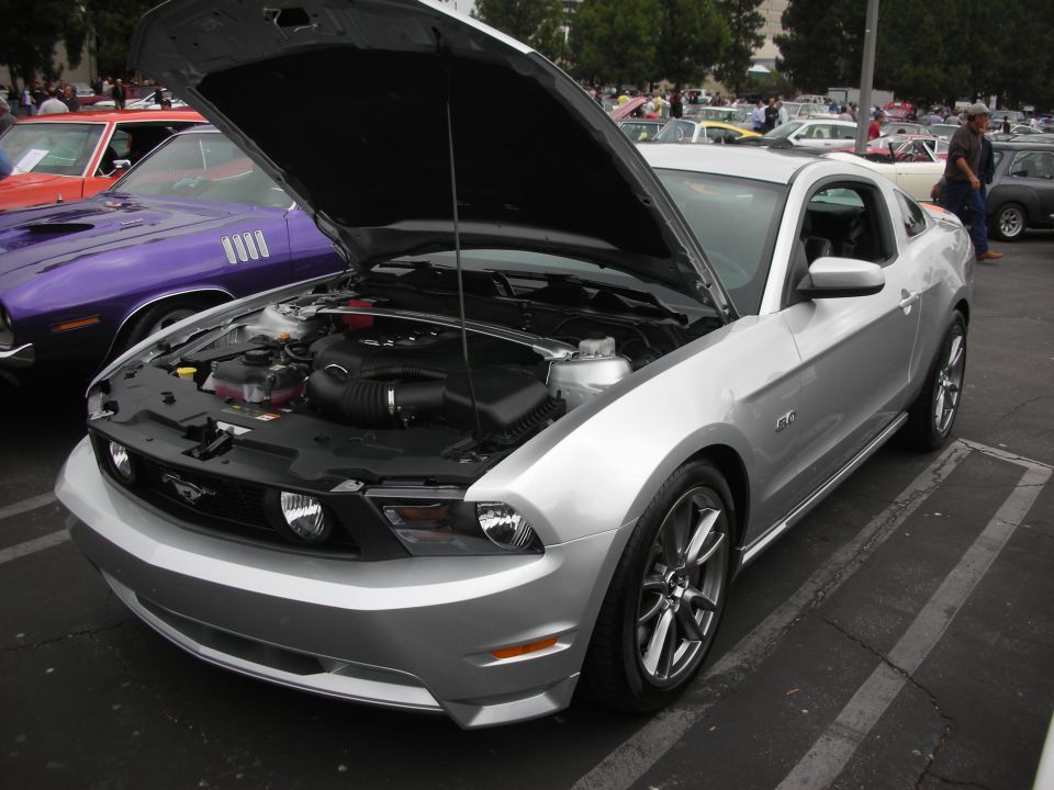 Silver Ford Mustang GT 5.0, hood open, showing engine. Front 3/4 view