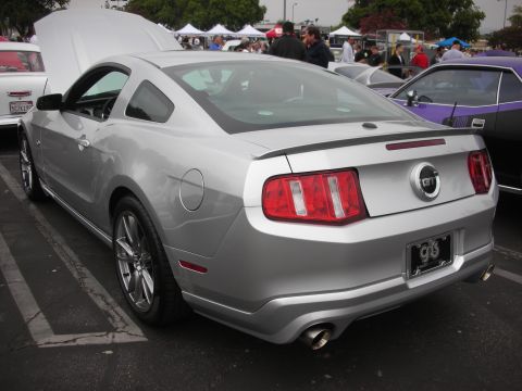 1998 Ford Crown Victoria - A silver Ford Mustang GT is parked at an outdoor event, with its hood up.