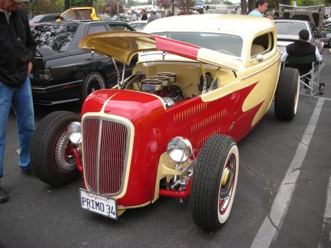 1998 Ford Crown Victoria - A custom hot rod with a prominent grille and flame graphics is parked at an outdoor event.