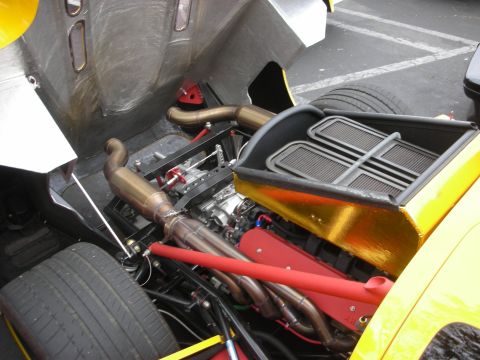 1998 Ford Crown Victoria - The engine bay of a yellow car reveals a V8 engine with custom exhaust and dual air intakes.