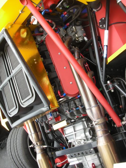1998 Ford Crown Victoria - Close-up view of a modified engine bay, a red roll cage, gold heat shielding, and custom exhaust components.