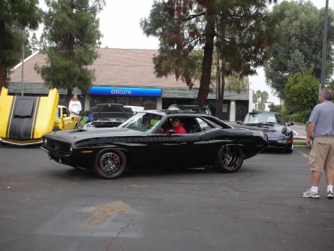 1998 Ford Crown Victoria - Black 1970 Plymouth Barracuda at a car meet with other vehicles present.