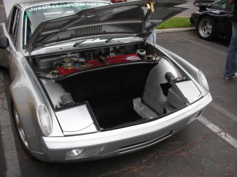 1998 Ford Crown Victoria - A silver sports car's front trunk is open, revealing its contents and a website sticker on the windshield.