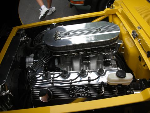 1998 Ford Crown Victoria - The engine bay of a yellow vehicle showcases a powerful Ford 427 SOHC engine with polished components.