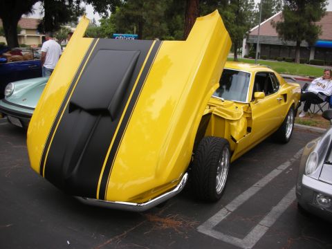 1998 Ford Crown Victoria - A yellow 1969 Ford Mustang Mach 1 is parked with its hood open, displaying black racing stripes.