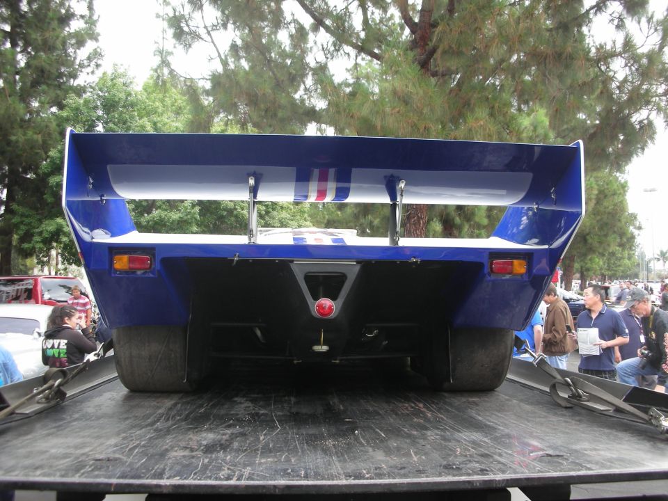 Blue race car rear view with large wing and red taillight
