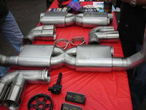 1998 Ford Crown Victoria - Various exhaust system components displayed on a table, including mufflers, pipes, and an ignition coil.