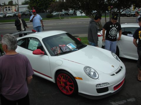 1998 Ford Crown Victoria - A white Porsche 911 with red trim and wheels is displayed at an outdoor gathering.