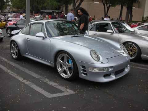 1998 Ford Crown Victoria - A silver Porsche 911 is parked next to another silver car at an outdoor gathering.