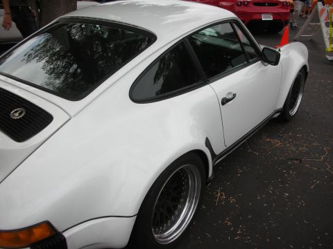 1998 Ford Crown Victoria - A white Porsche 911 is parked next to a red Ferrari at an outdoor car meet.