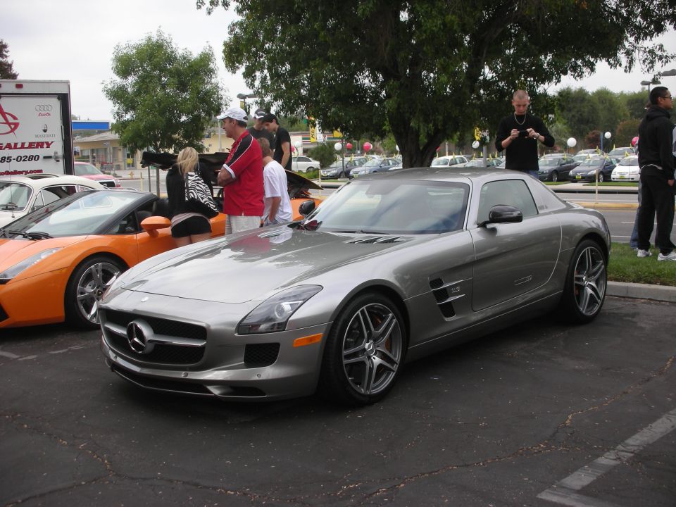Silver Mercedes-Benz SLS AMG coupe parked next to an orange Lamborghini