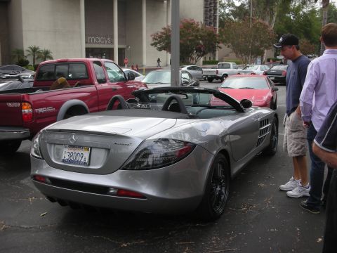 1998 Ford Crown Victoria - A silver convertible sports car with McLaren badging is parked in a lot near a Macy's department store.