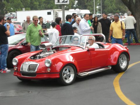 1998 Ford Crown Victoria - A crowd gathers around a modified red convertible with a prominent engine at an outdoor event.