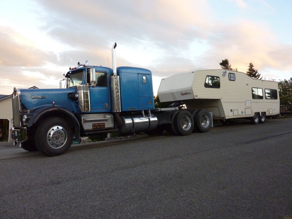Blue 1981 Kenworth W900A semi-truck towing a white RV
