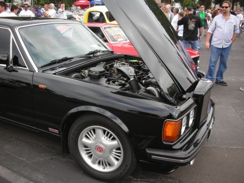 1998 Ford Crown Victoria - Black Bentley coupe with hood open at a car meet. Other vehicles and people are visible.
