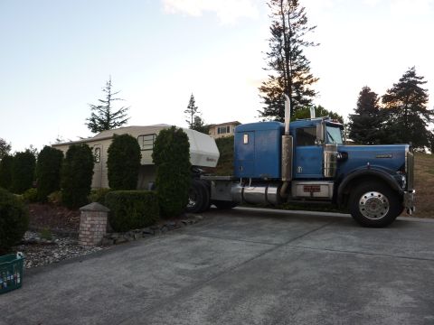 1981 Kenworth W900A - A blue 1981 Kenworth W900A semi-truck is parked on a driveway, attached to a white trailer.